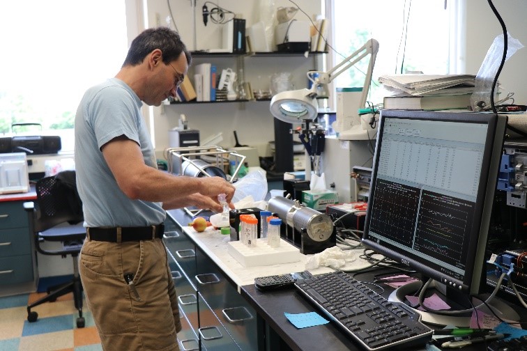 male researcher using instrument next to computer screen
