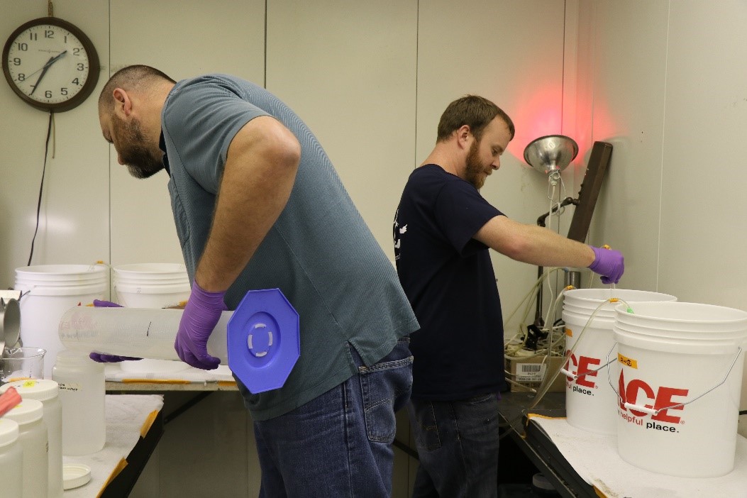 scientists pouring water into large buckets