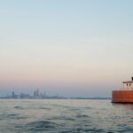photo of building in water with skyline of city in backgroun